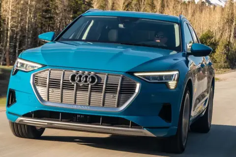 Blå Audi e-tron kör på en väg i skogen. En begagnad Audi e-tron som är perfekt för äventyr.