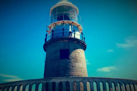 El faro de Corrubedo se alza imponente bajo un cielo azul intenso.