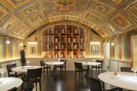 Interni eleganti con soffitto affrescato, libreria a vista e tavoli apparecchiati, un'atmosfera che evoca le stelle Michelin di Perbellini.