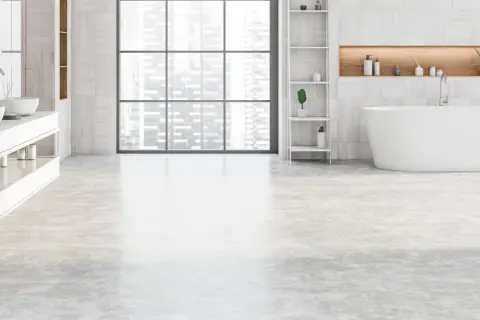 Salle de bain moderne avec baignoire îlot, double vasque et étagères. Le sol de la salle de bain est en béton ciré clair, apportant une touche contemporaine.