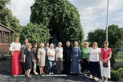 Grupa osób z księdzem i siostrą zakonną przy kapliczce Matki Bożej. Odnowa w duchu świętym zagrożenia, nadzieja w wierze.