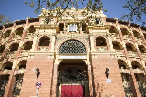 La imponente fachada de la plaza de toros de Zaragoza, con sus arcos y balcones, se alza bajo un cielo azul.