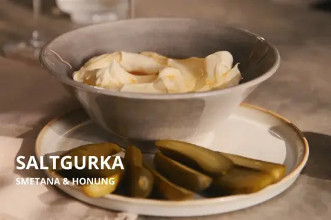 En skål med krämig smetana och honung, serverad med saltgurka. En oväntad men utsökt kombination.