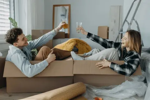 Pareja brindando dentro de cajas, listos para mudarse. ¡Qué alivio que mi casero quiere hacer obras y nos da esta oportunidad!