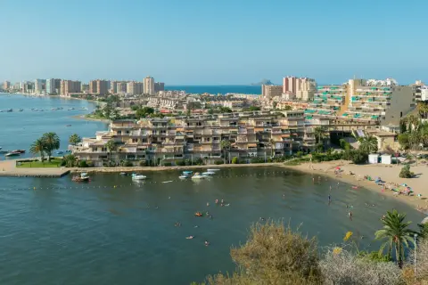 Widok na La Mangę z plażą, budynkami mieszkalnymi i łodziami na wodzie.