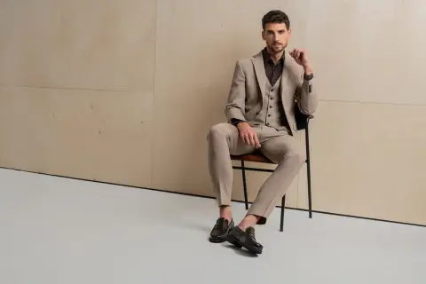 Elegancki mężczyzna w beżowym garniturze i kamizelce, idealny wybór, jaki garnitur dla blondyna.