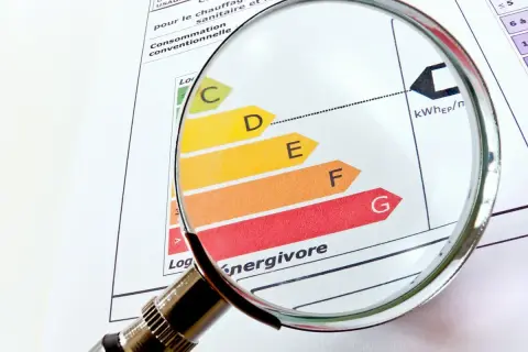 Loupe sur un diagnostic de performance énergétique (DPE). La classification de A à G, indiquant une interdiction location, est examinée.