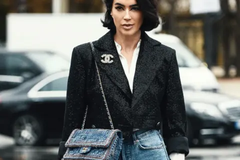 Elegancka kobieta w tweedowej marynarce i jeansach, z torebką Chanel. Klasyczne coco chanel stylizacje.