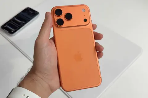Maintenant, un **iphone avec 4 caméras** orange est tenu dans une main.