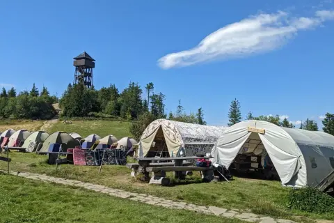 Obóz namiotowy na szlaku na Luboń z Kluszkowiec. Wieża widokowa w tle, namioty i ławki.