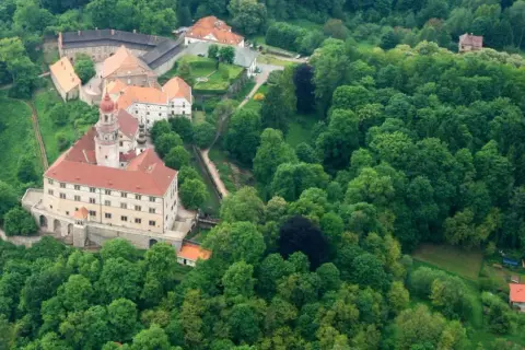 Zamek Nachod w Czechach, otoczony bujną zielenią, z charakterystyczną wieżą i czerwonymi dachami.