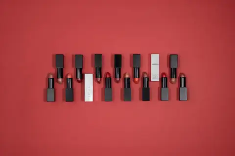 Une collection de rouges à lèvres aux teintes variées, dont un rouge rose éclatant, sur fond rouge.