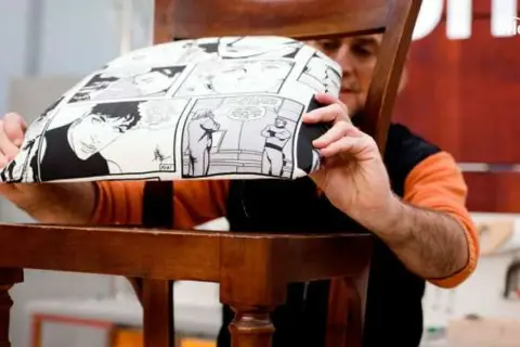 Hombre mostrando cómo tapizar una silla con tela de cómic.
