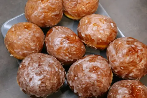Pyszne, rumiane pączki z piekarnika, oblane lukrem, kuszą swoim wyglądem. Idealne na tłusty czwartek!