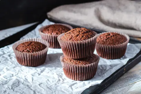 Fem chokladmuffins på ett bakplåtspapper. Perfekt för ett enkelt cupcakes recept.