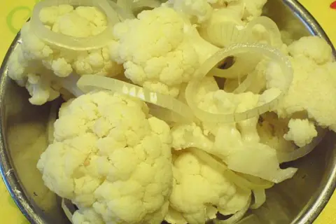 Blumenkohl und Zwiebelringe für blumenkohl sauer einlegen in einer Schüssel.