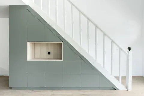 Aménagement sur mesure : un rangement sous escalier gris pâle avec des portes et une niche en bois clair.