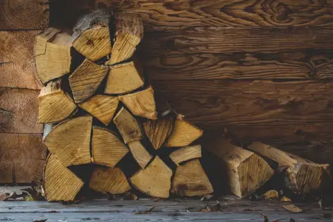 Gestapeltes Buchenbrennholz vor einer Holzwand. Die Frage, wie lange muss Buchenbrennholz trocknen, beschäftigt jeden, der gemütliche Wärme sucht.