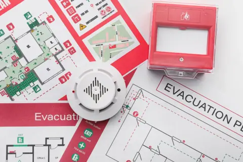 Piani di evacuazione e un rilevatore di fumo, elementi essenziali per la valutazione del rischio incendio.