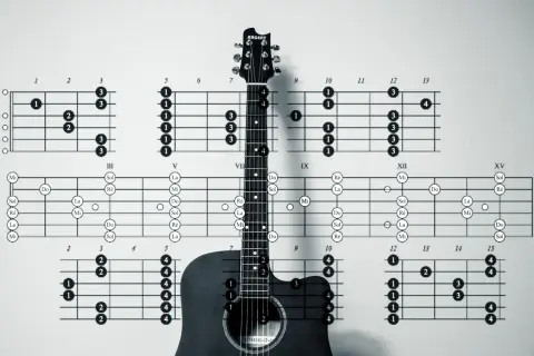 Czarno-białe zdjęcie gitary akustycznej z diagramami chwytów gitarowych.