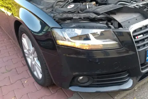 Audi A4 B8 przód: wymiana żarówki kierunkowskazu. Silnik odsłonięty, maska podniesiona.