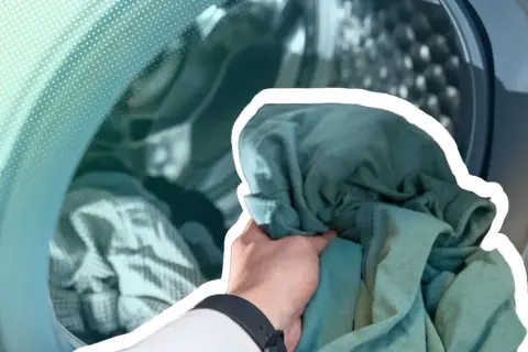 Hand lädt grüne Kleidung in eine Waschmaschine. Zeit, die neue Kleidung zu waschen und sie frisch zu machen.