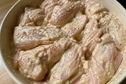 Råa kycklingbitar i en krämig marinad. Denna yoghurtmarinerade kyckling ser ut att bli otroligt saftig och smakrik.