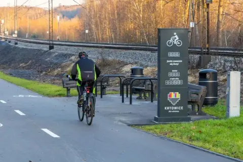 Rowerzyści na ścieżce wzdłuż torów kolejowych. Nowoczesne trasy rowerowe Śląsk zachęcają do aktywnego wypoczynku.