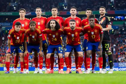 La selección española de fútbol posa en el campo. El equipo, con sus camisetas rojas y pantalones azules, muestra su unidad y determinación. Así ha quedado España en el fútbol, lista para la batalla.