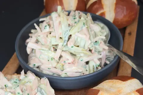 Ein cremiger Fleischsalat, perfekt für ein schnelles **Fleischsalat Rezept**. Serviert mit Laugenbrötchen.