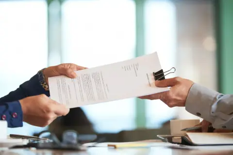 Dwie osoby przekazują sobie dokument "PARTNERSHIP AGREEMENT". To ważny moment, gdy ustalenia stają się faktem.