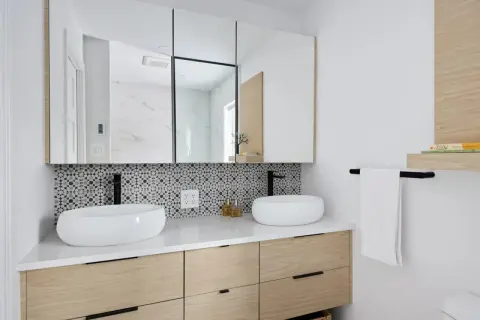 Meuble de salle de bain moderne avec deux vasques, carrelage géométrique et tiroirs en bois clair. Une belle idée meuble salle de bain à faire soi-même.