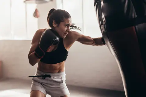 Focused female boxer practices double end bag drills, her punches a blur of motion.