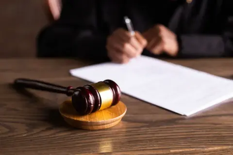 Młotek sędziowski na drewnianym stole, obok dokumenty. Sądowa decyzja o nieważności postępowania kpc zapadnie wkrótce.