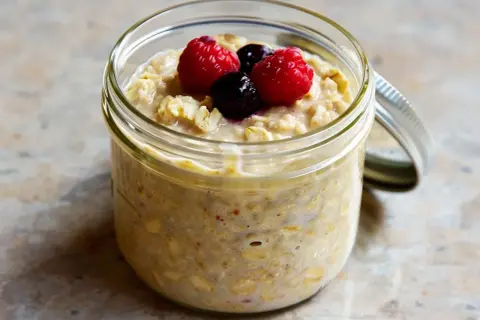 Overnight oats med proteinpulver i burk, toppad med hallon och blåbär. Perfekt för en snabb och näringsrik frukost.