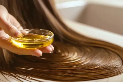 Dłoń trzymająca miseczkę z olejem, gotowa do olejowania włosów. Dowiedz się, jak zacząć tę pielęgnację.