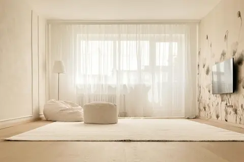 Jasne, przytulne wnętrze z dywanem, pufami i lampą. Eleganckie listwy okienne wewnętrzne podkreślają styl.
