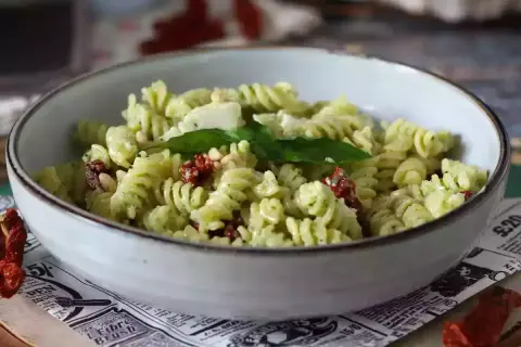 En skål med kall pastasallad med pesto, soltorkade tomater och pinjenötter. En perfekt sommarrätt.