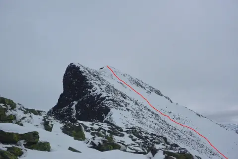 Snöklädda bergstoppar med en röd markerad led som leder uppåt. En utmanande sylarna topptur i vinterlandskap.