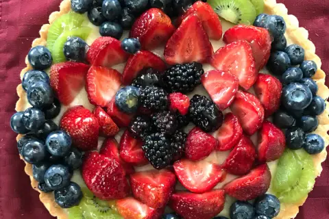 Kolorowa tarta z owocami: truskawki, borówki, jeżyny i kiwi.