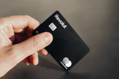 Dłoń trzyma czarną kartę Revolut Business z logo Mastercard.