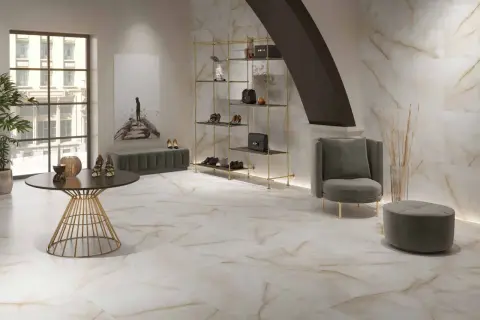 Elegantes suelos pintados con pintura imitan mármol veteado, complementando un salón moderno con estanterías doradas y mobiliario de terciopelo.