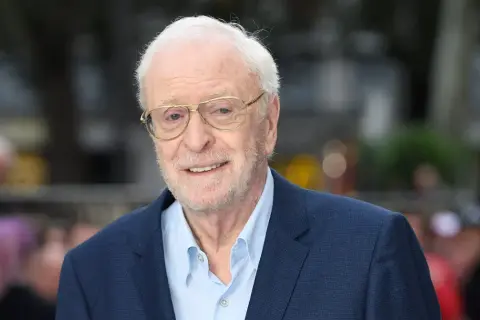 Uśmiechnięty Michael Caine w okularach, ikona kina. Jego niezapomniane role w licznych filmach na zawsze zapisały się w historii.