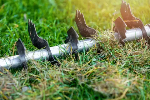 Metalowe ostrza aeratora w trawie, przygotowujące podłoże do lepszego wchłaniania składników odżywczych, kluczowych dla prawidłowej fertygacji.