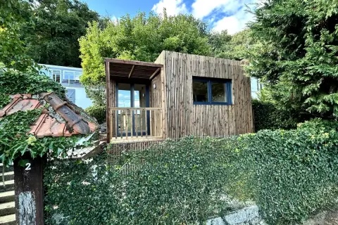 Une charmante tiny house en bois, nichée dans un jardin verdoyant, évoque un coin de nature paisible près de Paris.