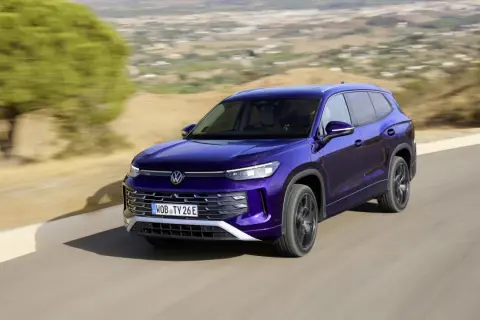 Fioletowy VW Tayron jedzie po krętej drodze wśród wzgórz.