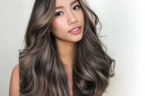 Mujer con cabello castaño oscuro con mechas balayage en tonos miel y ceniza. Las mechas lucen naturales y bien integradas, creando un efecto de profundidad y dimensión. La pregunta de cuanto duran las mechas es clave para mantener este look.