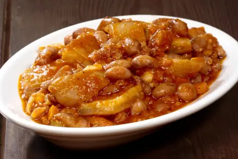 Piatto di fagioli con le cotiche, un classico della ricetta marchigiana, servito in una ciotola bianca su un tavolo di legno scuro.