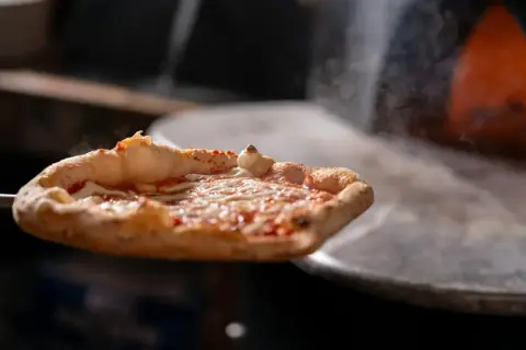 Gorąca pizza z serem i sosem pomidorowym wyjmowana z pieca.
