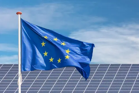 Bandera de la UE ondeando sobre placas solares en Extremadura, símbolo de ayudas para la energía limpia.